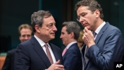 Dutch Finance Minister Jeroen Dijsselbloem, right, talks with European Central Bank Governor Mario Draghi during a meeting of eurogroup finance ministers at the European Council building in Brussels, March 9, 2015. 