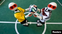 Humanoid robots dressed in the colors of Germany's and Brazil's national soccer team jerseys hold the official 2014 World Cup soccer ball during a photo opportunity at the Institute for Computer Science at the University of Bonn in Bonn June 18, 2014. 