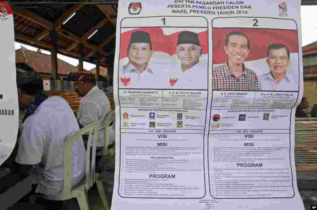 A poster with images of Indonesian presidential candidates with their running mates is displayed at a polling station in the presidential election in Bali, Indonesia, July 9, 2014.