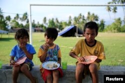 Children eat outside their tent for safety reasons after the earthquake in Biromaru village in Sigi, in Indonesia's Sulawesi island, Oct. 3, 2018.