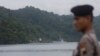Một cảnh sát Indonesia đứng gác ở Cilacap, miền trung Java, Indonesia trong khi một chiếc phà, cùng với các phương tiện chống đạn khác chở hai tù nhân người Australian đến đảo Nusakambangan island, 4/3/2015.
