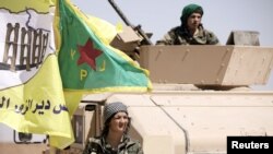 FILE - A female fighter from the Syrian Democratic Forces stands near a military tank in the village of Abu Fas, Hasaka province, Syria, Sept. 9, 2017. Abu Fas was the site of a triple car bomb blast Oct. 12, 2017, by Islamic State suicide attackers.