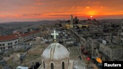 Kubah gereja Asyur yang menghadap menara masjid di Manger Square di Betlehem di Tepi Barat yang diduduki Israel, 24 Desember 2018. (Foto: Reuters/Mustafa Ganeyeh)