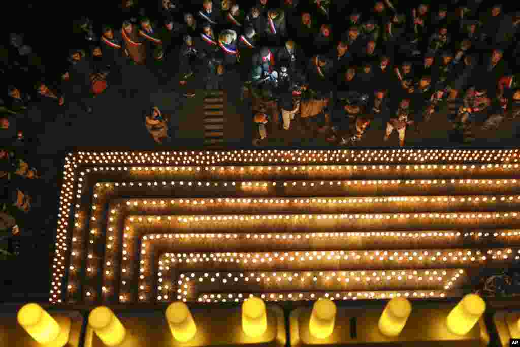 People gather near candles lit to commemorate the victims of a deadly attack at the Paris offices of French satirical weekly Charlie Hebdo in Lyon, central France, Jan. 7, 2015.
