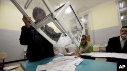 An election worker empties a ballot box to count votes after parliamentary elections at a polling station in Algiers, Algeria, May 10, 2012.