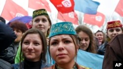 Crimean Tatars hold ATR TV station flags during a support rally in Simferopol, Crimea, March 31, 2015.