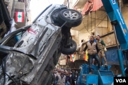 A crane lifts a car wrecked by one of the bombs. Many in the neighborhood said the attacks would not dampen their support for Hezbollah's military backing of the Syrian government.