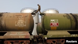 FILE - A worker walks atop a tanker wagon to check the freight level at an oil terminal on the outskirts of Kolkata, India.