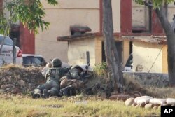 Indian soldiers take position as they surround the residential quarters where militants are believed to be holed up in an Army camp in Jammu, India, Feb. 11, 2018.