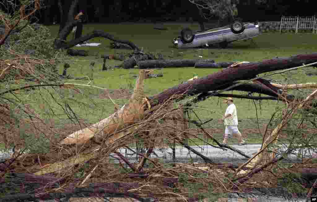 Seorang pria berjalan di sepanjang Sungai Blanco tempat banjir bandang memporakporanda kendaraan dan merobohkan pohon-pohon cemara di Wimberley, Texas, USA.