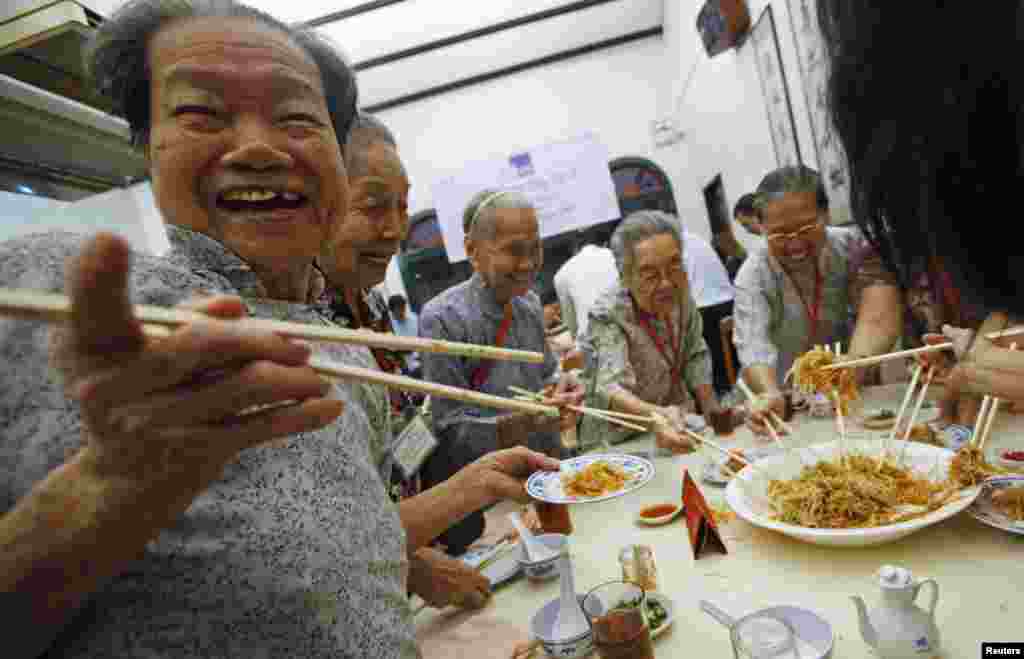 在農歷新年來臨之前，老年居民們在新加坡中國城一座餐館裡撈魚生。