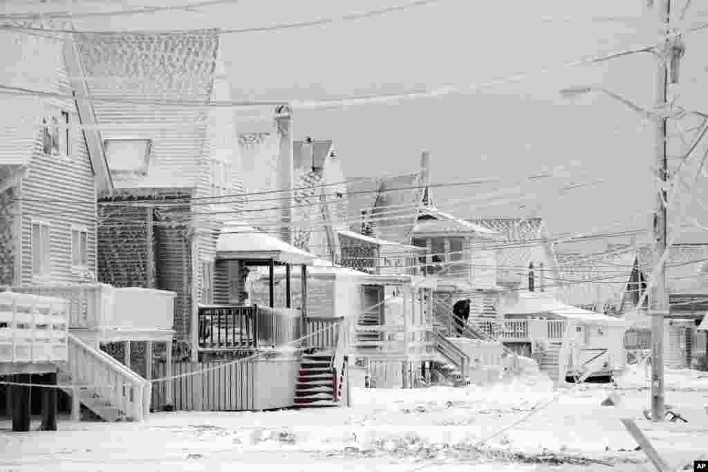 Dexter Newcomb begins cleanup at his house in Scituate, Massachusetts the day after a winter storm left his neighborhood coated in frozen sea spray, snow and sand.