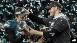 En esta foto del archivo de 4 de febrero de 2018, Carson Wentz (derecha), de los Eagles de Filadelfia, entrega el trofeo Vince Lombardi a Nick Foles, tras el triunfo en el Super Bowl LII sobre los Patriots de Nueva Inglaterra en Minneapolis ( AP Foto / Frank Franklin II)