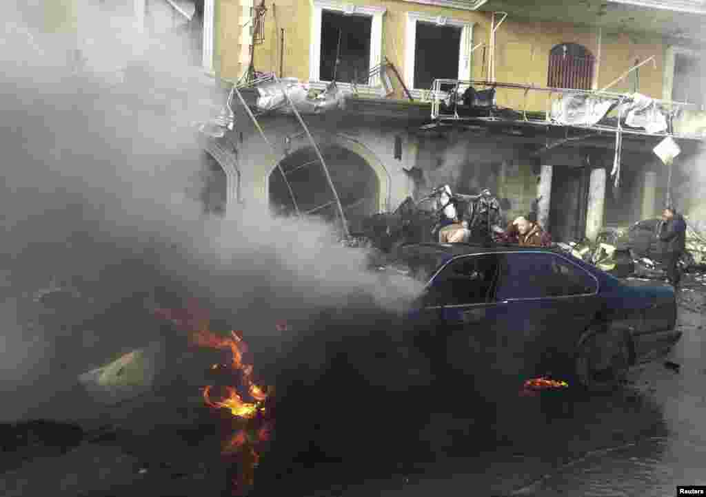Seorang pria dekat mobil yang terbakar di lokasi ledakan di kota Syiah di Hermel, 16 Januari 2014. 