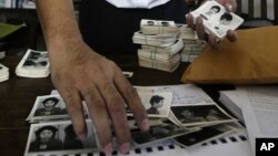 In this photo taken on Aug. 20, 2012, Director of Documentation Center of Cambodia, Youk Chhang arranges photos, a part of about a thousand of newly-discovered photo collection of detainees at the former Khmer Rouge main prison S-21, in his office in Phno