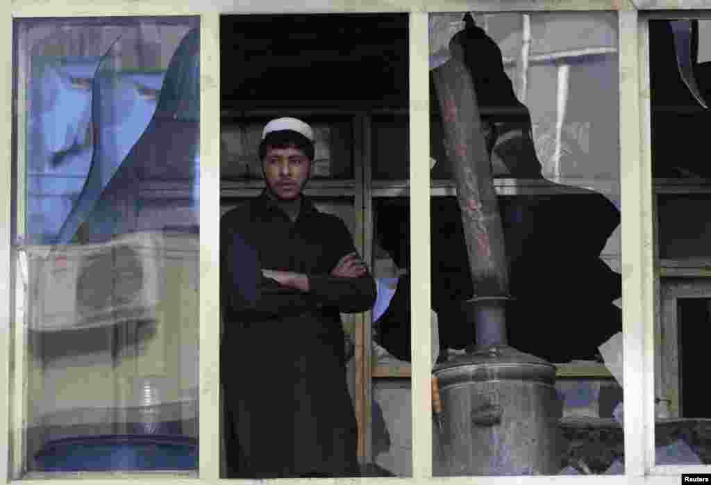 An Afghan man looks out a window at the site of a suicide car bomb attack in Jalalabad province, Afghanistan, March 20, 2014.