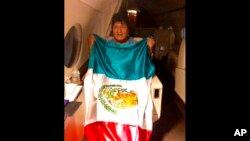 En esta imagen publicada por el ministro mexicano de Exteriores, Marcelo Ebrarde, se ve al expresidente de Bolivia Evo Morales sosteniendo una bandera mexicana a bordo de un avión de la Fuerza Aérea mexicana.
