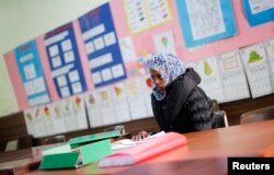 FILE - Amina, a migrant from Somalia, studies Italian at a school in Riace, Calabria region, Italy, Nov. 22, 2013.