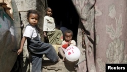 FILE - Children linger near their home in a poor neighborhood of Yemen's capital, Sanaa, Dec. 4, 2015. The NGO Human Rights Watch has condemned unlawful airstrikes that kill civilians.