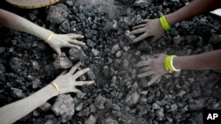 FILE - Indian women use bare hands to pick reusable pieces from heaps of used coal discarded by a carbon factory in Gauhati, India, Dec. 14, 2015. Thirteen young miners were missing and feared dead in India's remote northeast, police said Friday, Dec. 14, 2018.