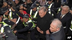 Cardinal George Pell, center right, is surrounded by police as he arrives at the Melbourne Magistrates Court in Melbourne, Australia, July 26, 2017. 