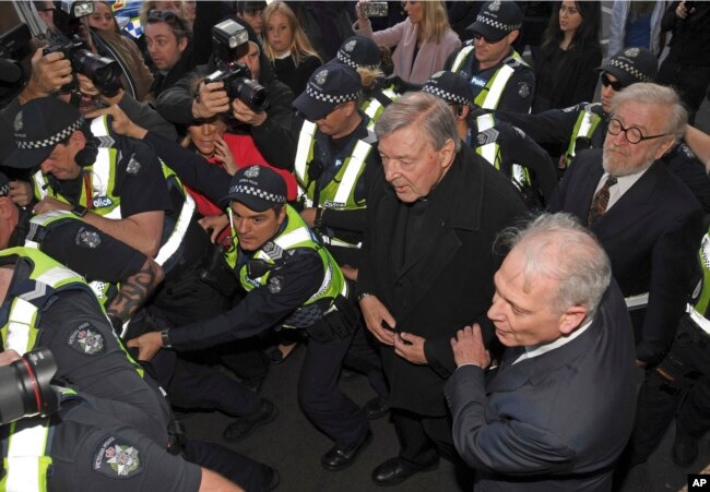 FILE - Cardinal George Pell, center right, is surrounded by police as he arrives at the Melbourne Magistrates Court in Melbourne, Australia, July 26, 2017.