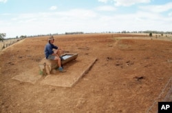 FILE - Farmer Andrew Higham looks over his parched land on his Gunnedah property in northwestern New South Wales, Australia.