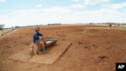 FILE - Farmer Andrew Higham looks over his parched land on his Gunnedah property in northwestern New South Wales, Australia.