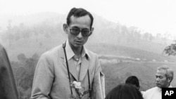 Thai King Bhumibol Adulyadej receives a small rose plant from a woman as he makes a visit to one of his crop substitution projects in Northern Thailand, Feb. 16, 1981.