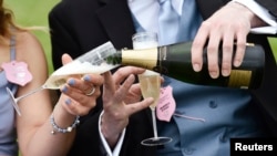 FILE - Racegoers pouring champagne. 