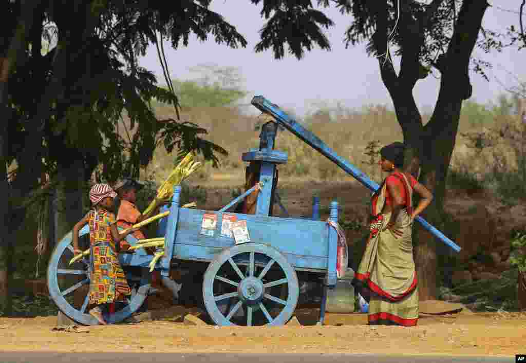 Children help a woman to extract juice from sugarcane to sell by a roadside on the outskirts of Hyderabad, India.