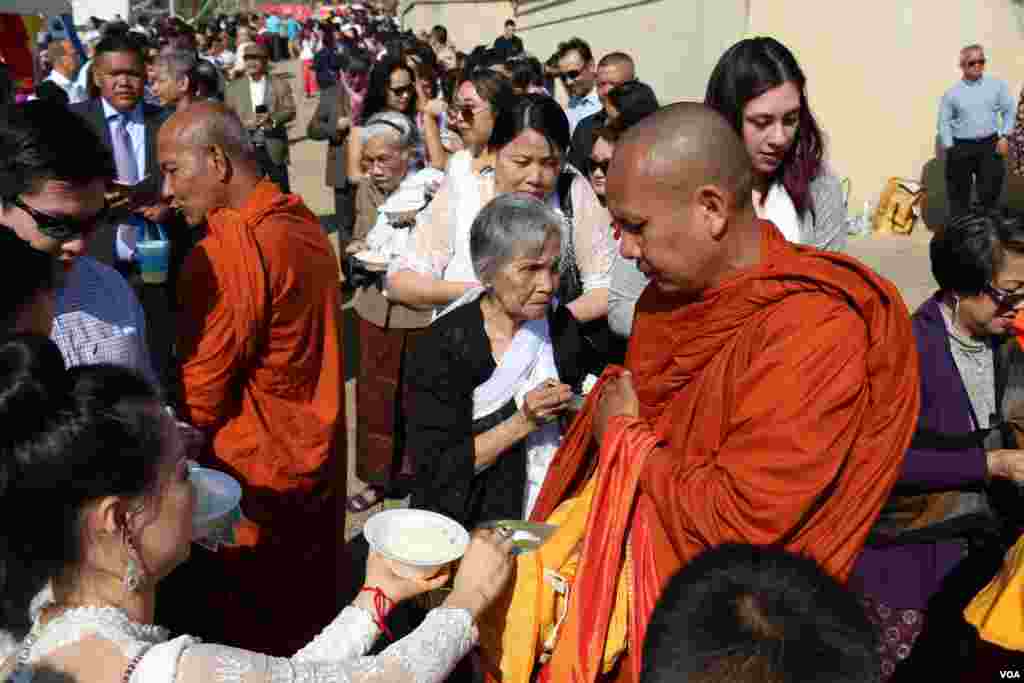 អ្នកកាន់ពុទ្ធសាសនាប្រគេនម្ហូបអាហារនិងប្រាក់កាសដល់ព្រះសង្ឃ។ (ចាប ចិត្រា/VOA)