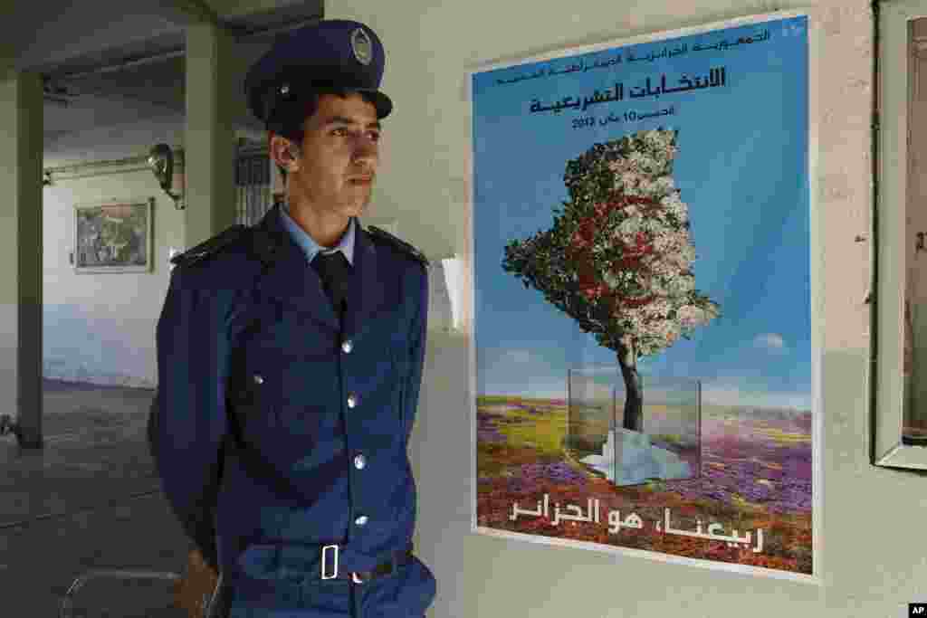 A policeman stands guard at the entrance of a polling station during parliamentary elections on the outskirts of Algiers.