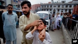 A man helps an injured boy to a hospital after an earthquake hit Peshawar, Pakistan, April 10, 2016. 