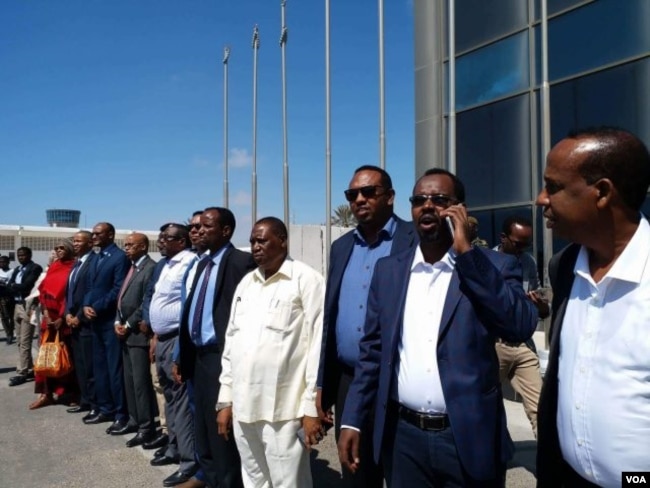 Somali officials line up at Mogadishu's airport to welcome Somali migrants from Libya, Feb. 17, 2018. (H.K. Qoyste/VOA)