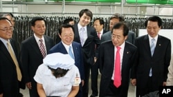 South Korea's ruling Grand National Party chief Hong Joon-pyo, second from right, looks at a North Korean worker during his visit to a factory in the inter-Korean industrial park in Kaesong, North Korea, September 30, 2011.