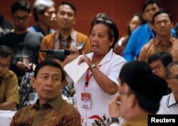 Bali bombing survivor Chusnul Khotimah stands behind Indonesia Chief Security Minister Wiranto as she speaks during a meeting between former militants and victims in Jakarta, Indonesia, Feb. 28, 2018.