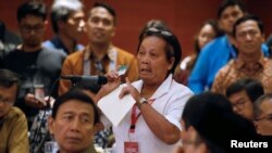Bali bombing survivor Chusnul Khotimah stands behind Indonesia Chief Security Minister Wiranto as she speaks during a meeting between former militants and victims in Jakarta, Indonesia, Feb. 28, 2018.