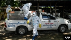 Volunteers wearing personal protective equipment (PPE) prepare to transport the body of a victim of the Covid-19 coronavirus to a cemetery in Hlegu Township in Yangon on July 10, 2021. (Photo by Ye Aung THU / AFP)