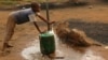 FILE - A child fills a container with water for domestic use in Delmas, east of Johannesburg, South Africa.