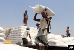 FILE - In this Sept. 21, 2018 photo, men deliver U.N. World Food Programme (WFP) aid in Aslam, Hajjah, Yemen.
