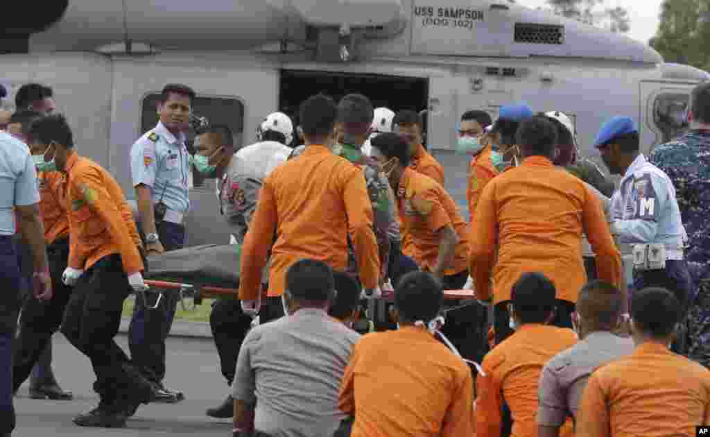 Anggota Tim SAR dan polisi Indonesia mengangkat jenazah korban AirAsia 8501 dari helikopter Angkatan Laut AS milik kapal induk Amerika USS Sampson setibanya di bandara Pangkalan Bun, Indonesia (2/1).