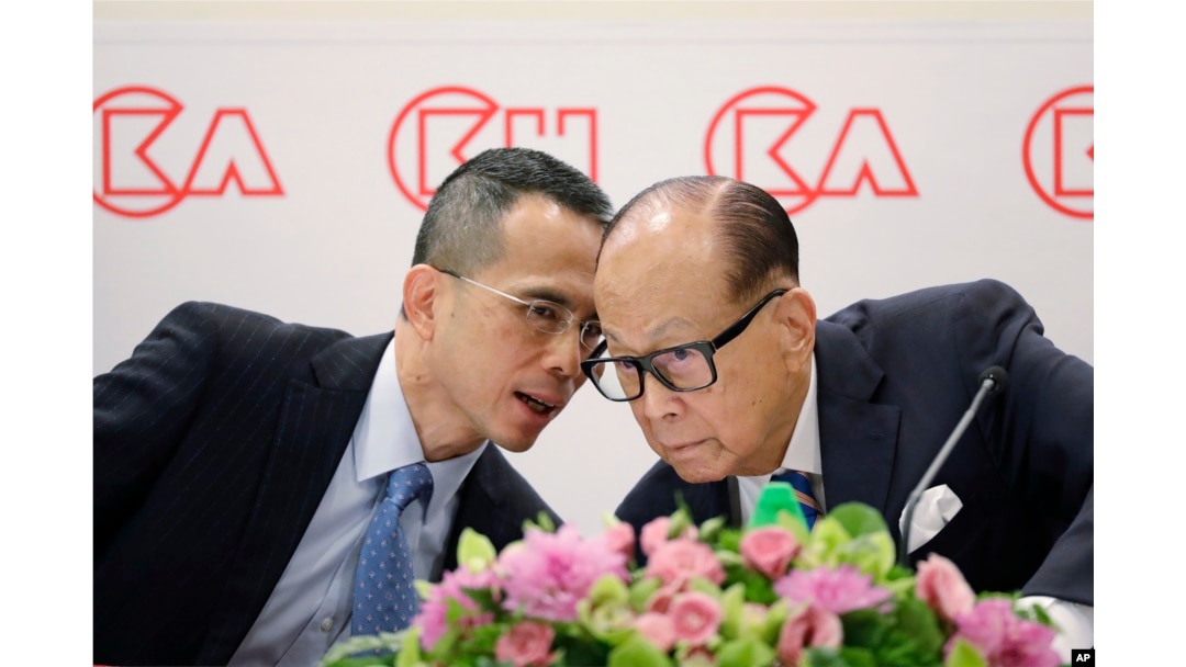 Hong Kong tycoon Li Ka-shing, right, chairman of CK Hutchison Holdings company, chats with his son, co-managing director Victor Li, at a press conference to announce the company's annual results in Hong Kong, March 16, 2018.