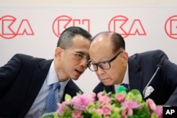 FILE - Hong Kong tycoon Li Ka-shing, right, chairman of CK Hutchison Holdings company, chats with his son, co-managing director Victor Li, at a press conference to announce the company's annual results in Hong Kong, March 16, 2018.