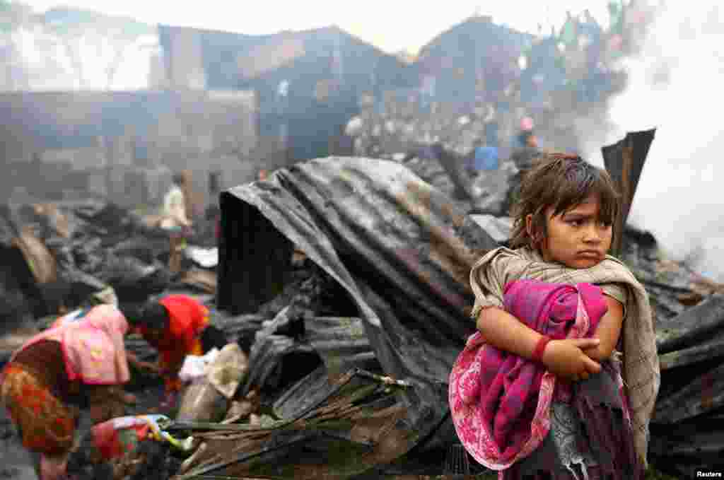 A child looks on, whose shelter burned after a fire broke out in a slum in Dhaka, Bangladesh.