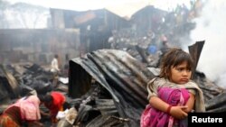 A child looks on, whose shelter burned after a fire broke out in a slum in Dhaka, Bangladesh.