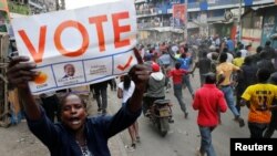 A supporter of Kenyan opposition leader Raila Odinga carries a banner and shouts slogans as others run along a street in Humura neighbourhood, in Nairobi, Kenya August 10, 2017.