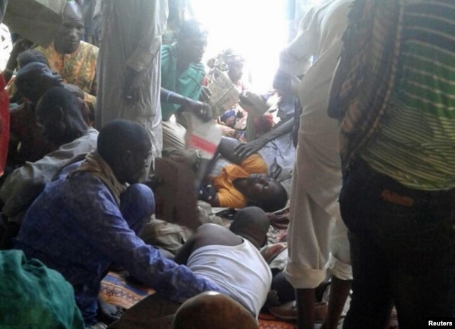 Injured people are comforted at the site of a bombing attack of an internally displaced persons camp in Rann, Nigeria, Jan. 17, 2017.