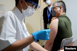 FILE - A local receives a booster shot of the Moderna coronavirus vaccine at a center operated by Japanese Self-Defense Force, in Tokyo, Japan, January 31, 2022. (Eugene Hoshiko/Pool via REUTERS)