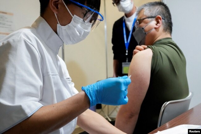 FILE - A local receives a booster shot of the Moderna coronavirus vaccine at a center operated by Japanese Self-Defense Force, in Tokyo, Japan, January 31, 2022. (Eugene Hoshiko/Pool via REUTERS)